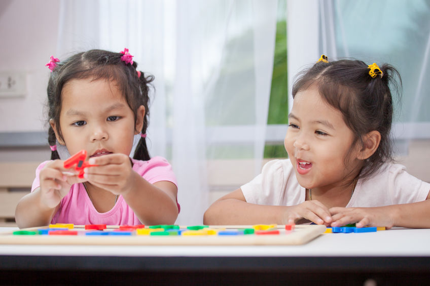 Two pre-school aged girls playing a game with magnets